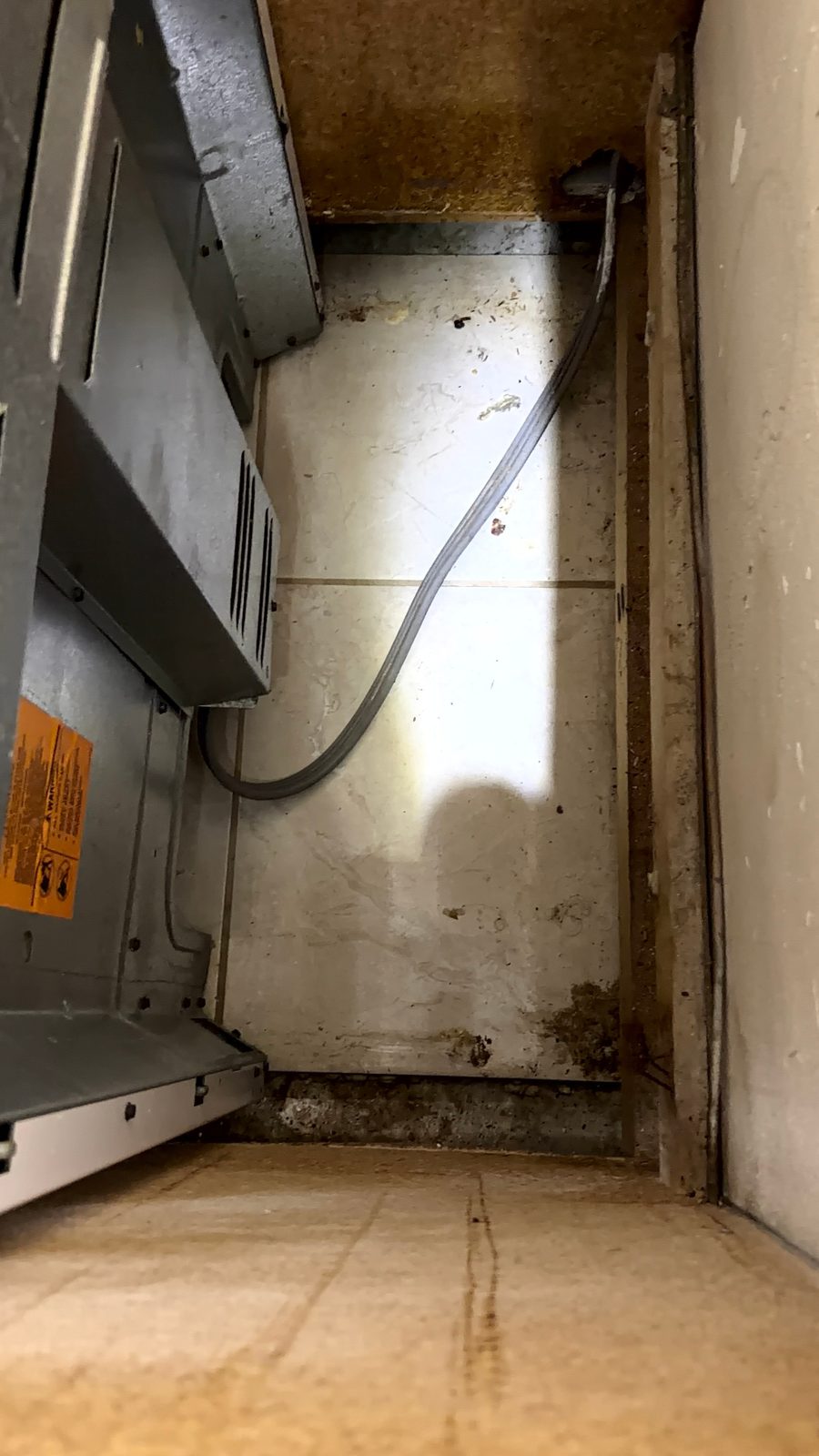 Floor-level view inside an air handler closet showing staining along the wall to floor joint