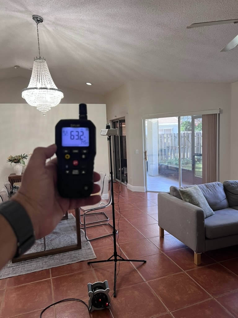 Air sampling equipment set up on a tripod in a living room during an indoor air quality assessment