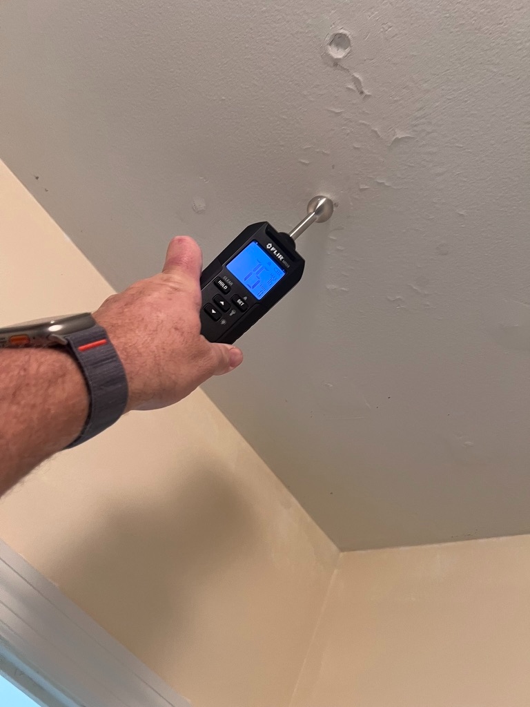 Moisture meter reading taken at a ceiling stain to investigate a suspected leak