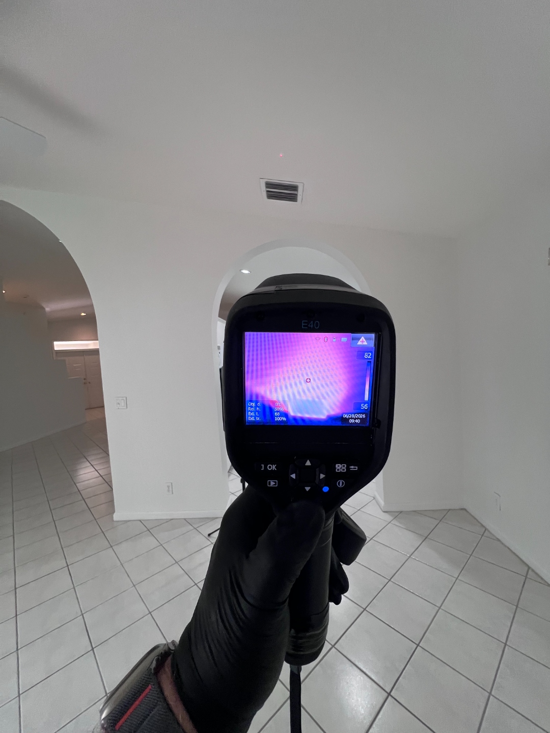 FLIR thermal imaging camera showing a ceiling temperature scan near a supply vent in the home's main living area