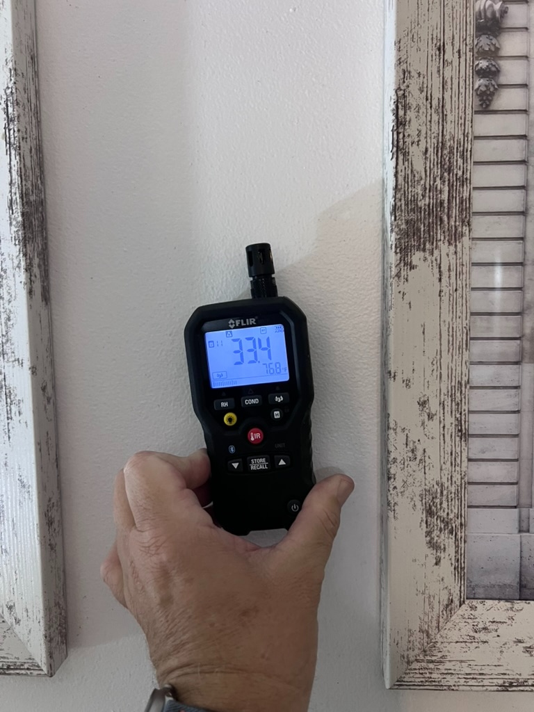 FLIR pinless moisture meter reading 33.4% moisture content on the affected dining room wall