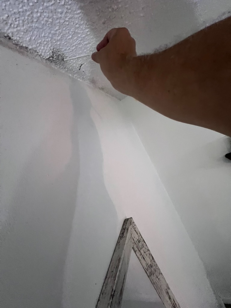 Inspector using a swab to collect a sample at the ceiling access opening near the master bathroom shower